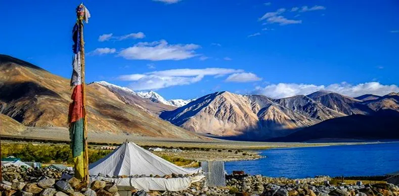 Pangong Lake, Ladakh: Buddhist prayer flags and tents with majestic mountains