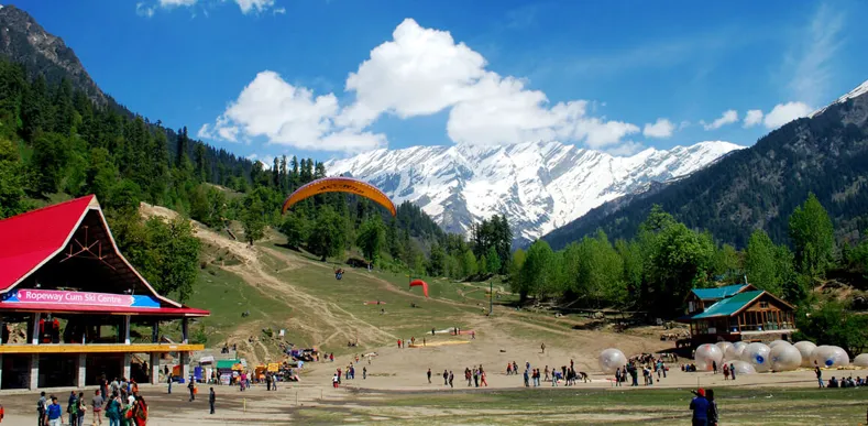 Solang Valley paragliding with snow-capped mountains and green slopes