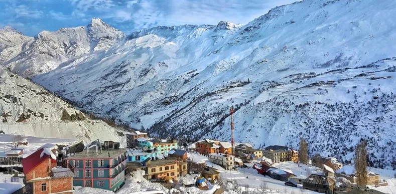 Snow-covered village nestled in a Himalayan valley with majestic mountains