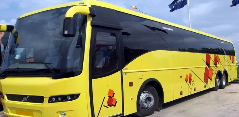 Bright yellow Volvo coach bus with red graphic accents parked outdoors.